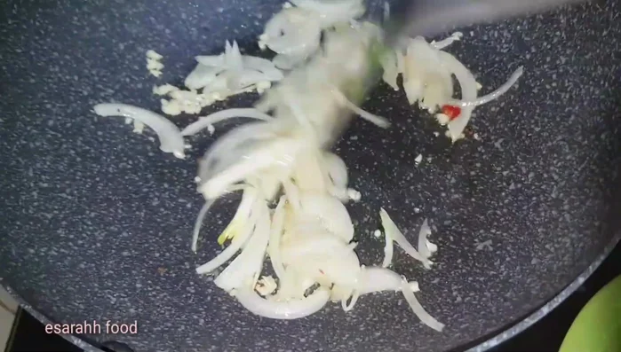 In the same wok, stir-fry onions, garlic, and chilies.