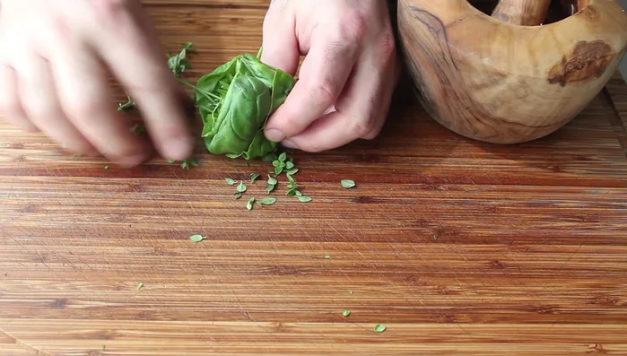 Roughly chop the herbs (start with largest basil leaves to bind). Add to the mortar and pestle and crush with the garlic mixture.