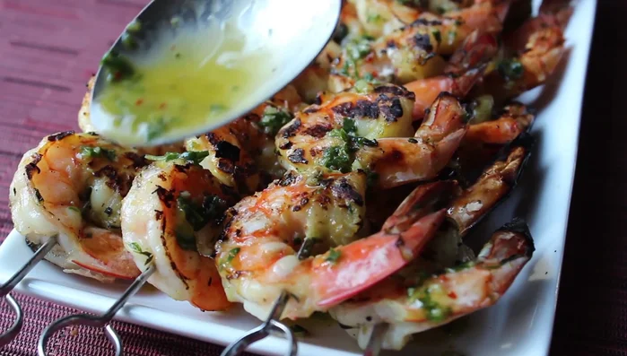 Spoon the sauce over the grilled shrimp and garnish with lemon wedges.