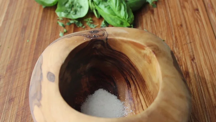 In a mortar and pestle, crush together kosher salt, a little lemon zest, and sliced garlic.