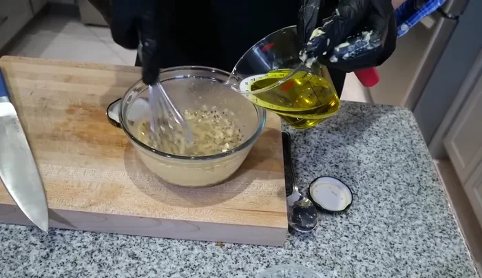 Slowly drizzle in the olive oil while whisking constantly to create an emulsion.