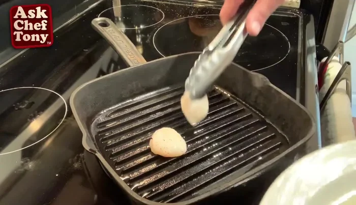 Sear the scallops in a hot pan until golden brown.