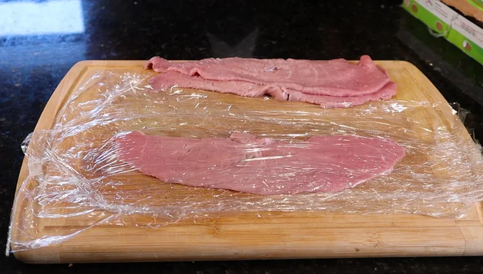 Pound the veal thinly between two pieces of Saran Wrap until it stretches past the edges of your dinner plate. (97.6)