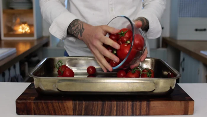 Place tomatoes, chilies, shallots, and garlic on a large baking tray (0:13.28).