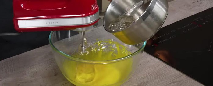 When the syrup reaches 121°C, slowly pour it into the yolks while whisking on low speed to prevent splashing.