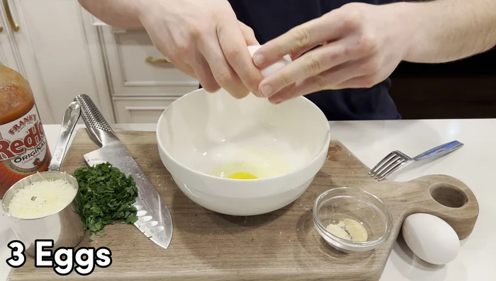 In a medium bowl, crack 3 eggs. Beat eggs and add parsley, cheese, 4 tsp each of garlic and onion powder, and a few dashes of Frank’s RedHot Sauce. Mix well.