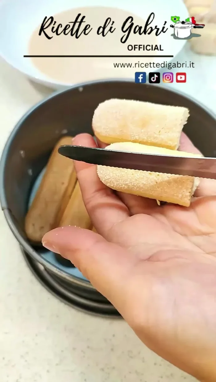 Cut biscuits in half to create the cake's edge. Arrange them along the circumference of the mold and press down on the base. Fill in any gaps with small biscuit pieces. [48.44]