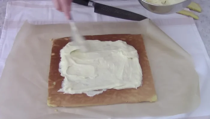 Spread half of the diplomatica cream on the biscuit, leaving space at the edges. Roll up the biscuit using the baking paper.