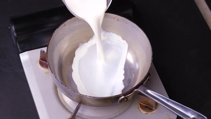 While meatballs are baking, prepare the polenta. In a saucepan, bring milk, heavy cream, and water to a boil.