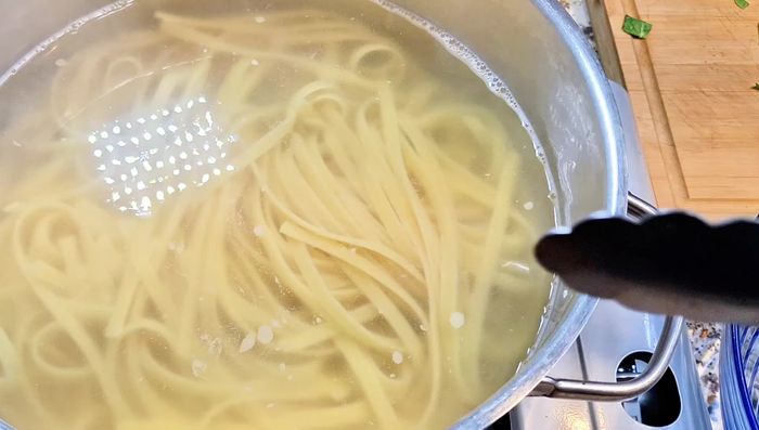 While the shrimp cooks, prepare the Alfredo sauce: In a pan, combine softened butter (room temperature for easy mixing) and pasta water. Stir constantly.