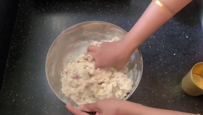 Gradually add 4 cups of lukewarm water, kneading the dough until it forms a ball.