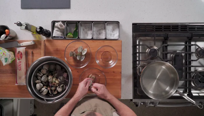 Prepare the sauce: Strain the clam juice, removing any sand or grit. In a pan, combine some clams, butter, garlic, and olive oil. Simmer and puree.
