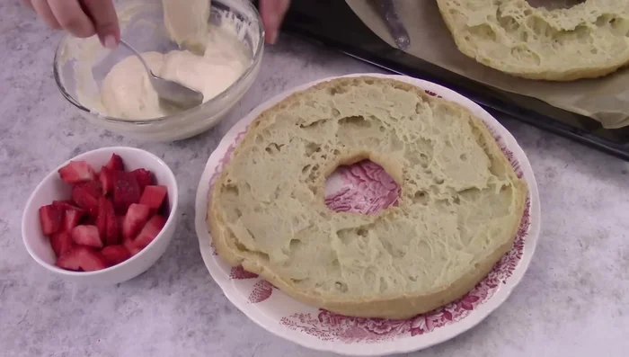 Cut the zeppolone in half, spread with cream, add strawberries, and top with the other half.