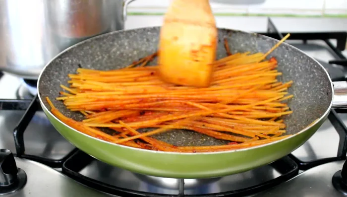 Add a couple of ladles of the tomato broth to the toasted spaghetti. Continue cooking, adding more broth only when the previous addition has been absorbed, and the spaghetti start to stick to the pan.