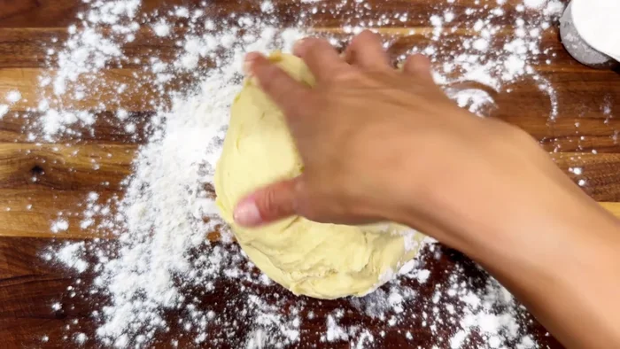 Place the dough on a lightly floured surface and knead for 3-4 minutes. Shape into a ball, cover with a dish towel, and let rest for 10 minutes.