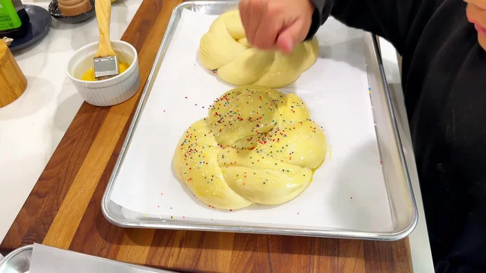 Add sprinkles and a dyed egg to the center of each ring. Do not press the egg into the dough.