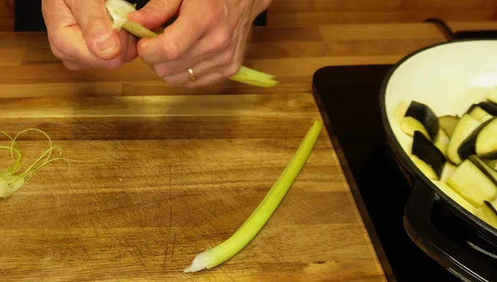 Prepare celery (remove strings), chop into similar size as eggplant, add to the pan.