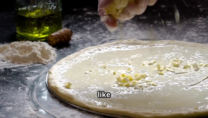 Dust pizza peel with cornmeal. Transfer stretched dough onto peel. Spread sauce in a spiral, leaving a border.