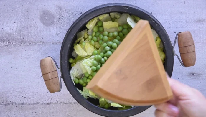 Layer the bottom of the pot with sliced lettuce, then broad beans, peas, and artichokes, seasoning each layer.