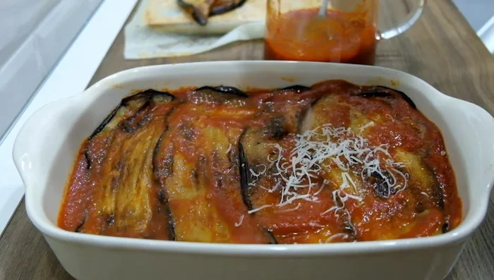 Finish with a final layer of tomato sauce, sprinkle with Parmesan cheese, and garnish with basil leaves.