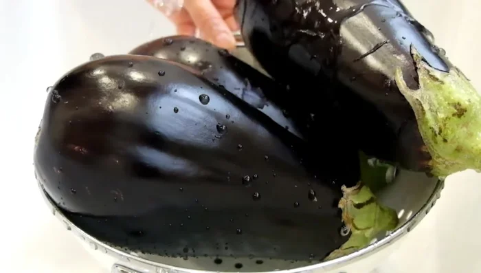 Wash the eggplants thoroughly, discard the stems, and slice them lengthwise into approximately 4 mm thick slices. Cutting them in half first makes it easier to achieve uniform slices.