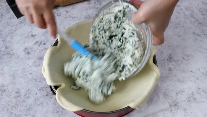 Spread the filling evenly inside the pastry shell. Make four indentations in the ricotta and crack an egg into each.