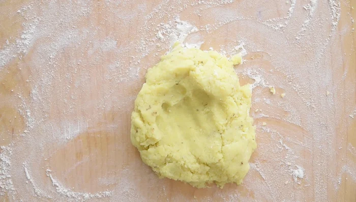 Lightly flour a work surface. Place mashed potatoes in a mound with a hole in the center. Sprinkle most of the flour over the potatoes (all-purpose for fluffy, all-purpose semolina for chunky).
