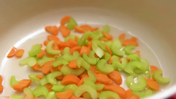 Sauté the chopped celery and carrots over medium heat until translucent.