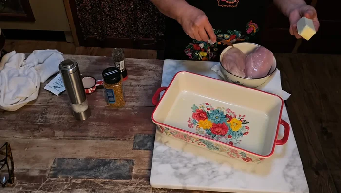 Preheat oven to 350°F (175°C). Place butter slices in the baking dish. Top with chicken breasts.