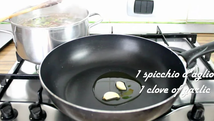 In a separate pan, fry a clove of garlic (halved) and chili pepper (optional) in oil until golden.