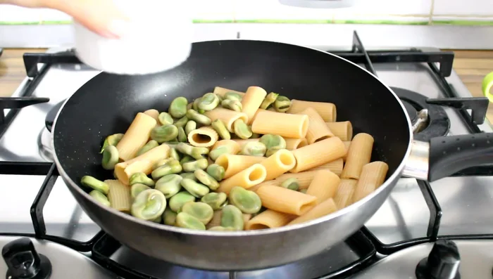 Drain pasta and broad beans, add to the pan with the garlic oil, and mix in some pasta cooking water.