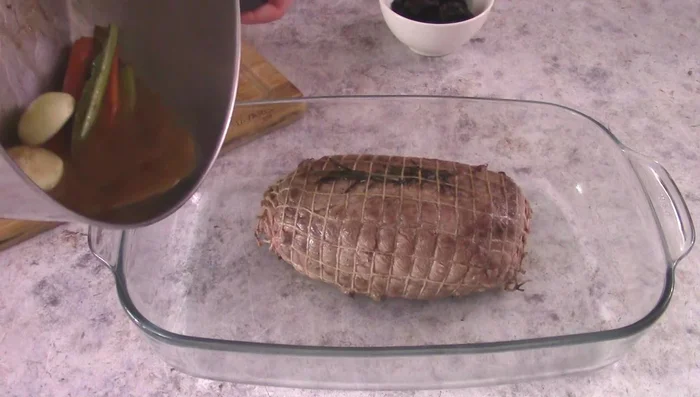 Transfer the roast to a baking dish, add cooking juices and herbs, 200ml broth. Bake at 200°C for 40 minutes.