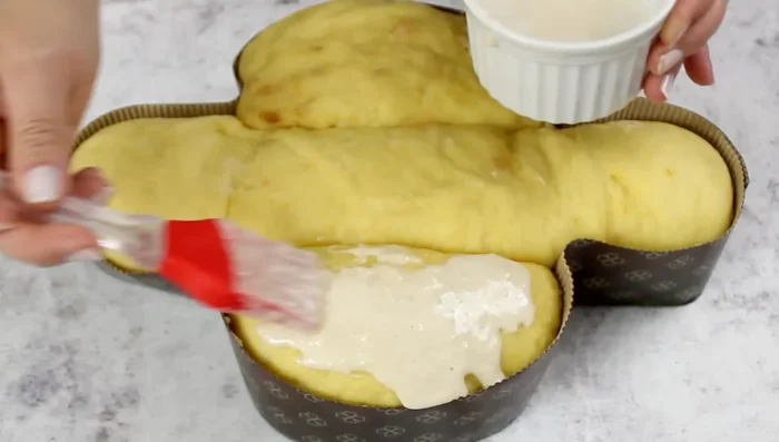 Brush the risen colomba with the icing, then sprinkle with granulated sugar and whole almonds.