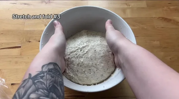 Perform the final set of stretch and folds using a coil fold technique to keep the cheese inside. Cover the dough.