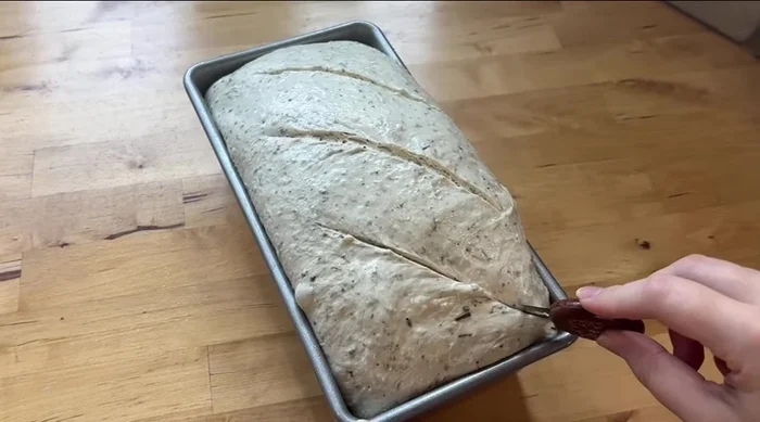 Preheat oven to 400°. Score the dough with three diagonal cuts. Sprinkle the remaining 30g of cheese on top. Use the double pan method (invert a second bread pan on top or use greased foil).
