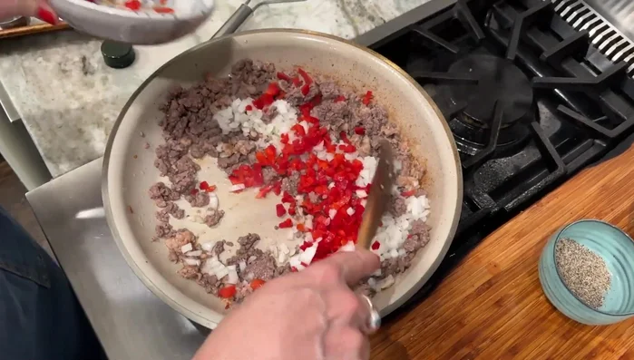 Add celery, red onion, and red bell pepper to the meat mixture.