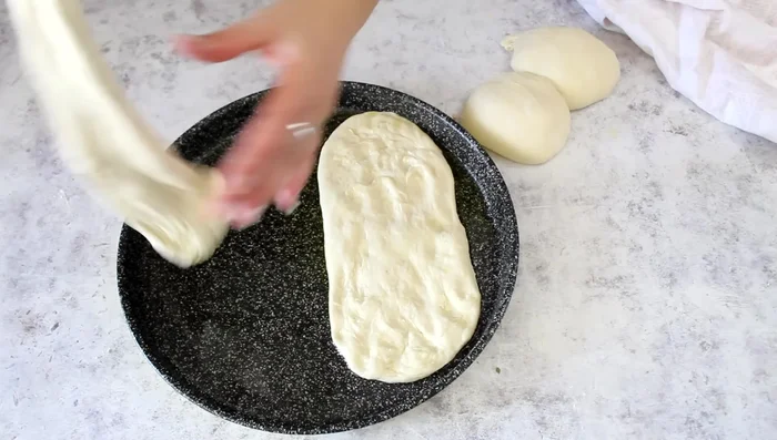 Assemble the pizza tongues: Roll out each dough ball into a thin oval shape. Spread tomato sauce, season with salt and oregano, and drizzle with olive oil.