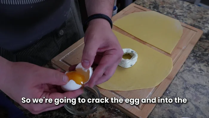 Carefully crack an egg yolk into the center of each ricotta circle. Gently spread the remaining pasta dough on top, sealing the edges to create the raviolo.
