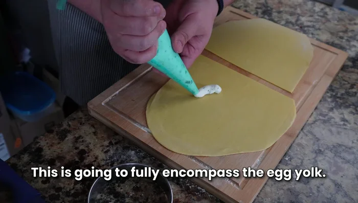 Pipe the ricotta mixture onto half of the rolled-out pasta dough, creating a circle leaving space for the egg yolk.