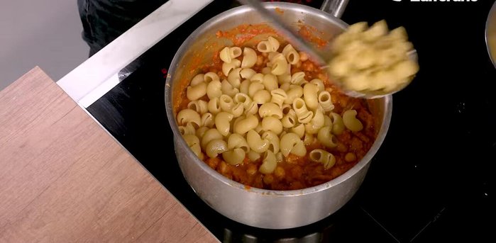 When the pasta is al dente, transfer it to the saucepan and stir.