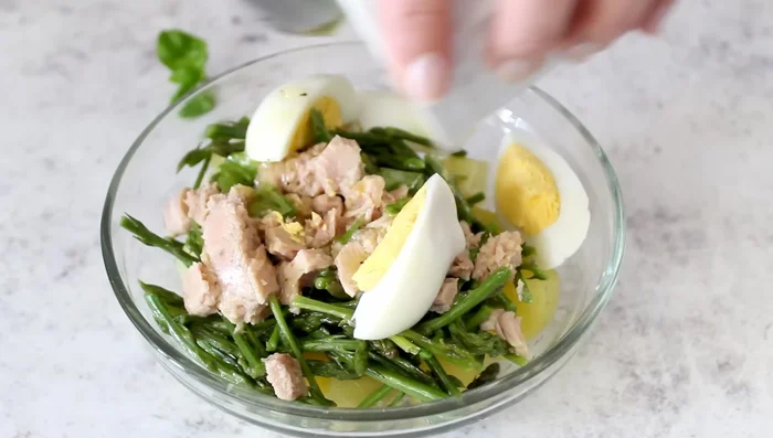 Dress the potato, tuna, asparagus, and egg salad.