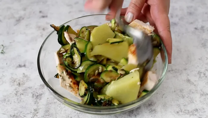 Dress the potato, chicken, and courgette salad.
