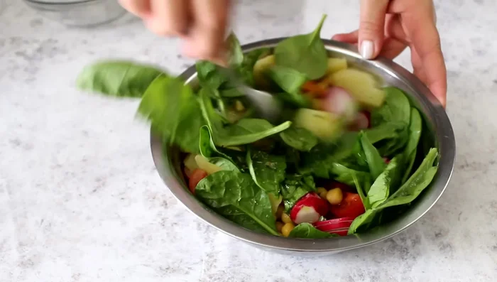 Dress the potato, chickpea, tomato, and radish salad.