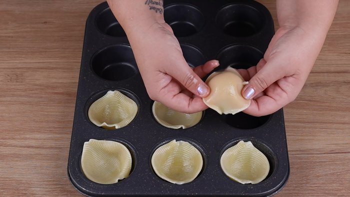Flip each pasta shell and place it into a muffin tin.