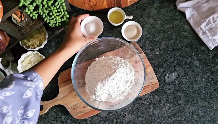 In a mixing bowl, add flour, salt, sugar, and instant yeast. Exact measurements are in the video description.