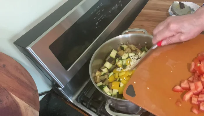 Add yellow peppers, garlic, and chopped tomatoes to the pan.