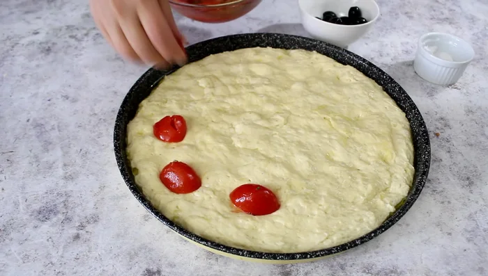 Spread the tomatoes and olives over the focaccia dough.