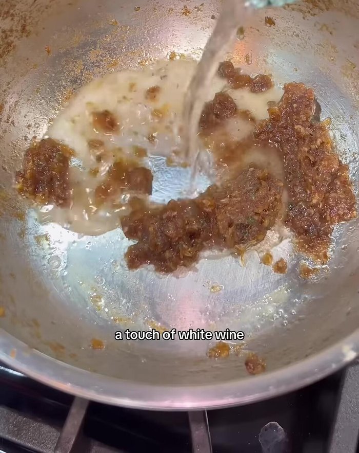 Deglaze the pan with white wine, scraping up brown bits.