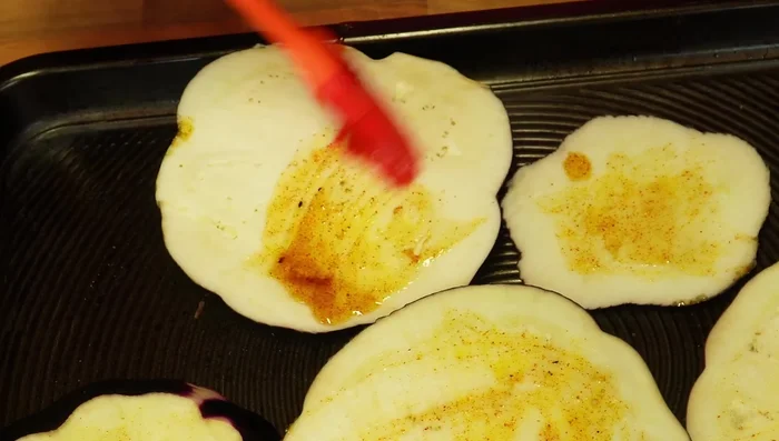 Brush the eggplant slices with the marinade on both sides and place them on oven trays.