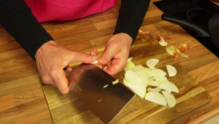 In a frying pan, sauté sliced white onion and thinly sliced garlic until soft.